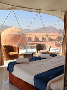 a bed and two chairs in a room with a large window at Omar wadi rum camp in Wadi Rum