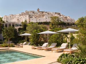 a pool with chairs and umbrellas in front of a building at VISTA Ostuni in Ostuni