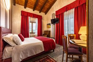 a bedroom with red curtains and a bed and a desk at Hotel & Restaurant Le Charaban in Aosta