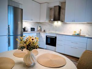 a kitchen with a table with a vase of flowers on it at Comfort Stay Apartments 1 in Katrineholm +3 photos