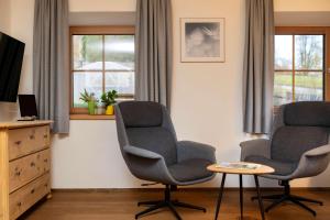 Dos sillas y una mesa en una habitación con ventanas. en Schmied in Oberdrum, en Oberlienz