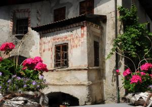 una casa vieja con flores delante en Reiterhof Siglgut, en Tarres