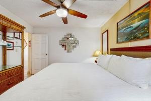 a bedroom with a white bed with a ceiling fan at Island Sands Resort 103 in Maalaea