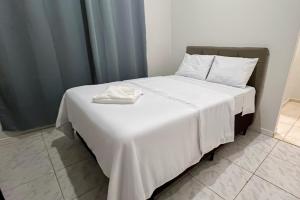 a bed with white sheets and towels on it at Suite Campina - Business Hotel in Campina do Monte Alegre