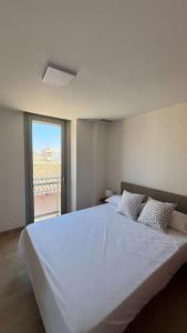 ein großes weißes Bett in einem Zimmer mit Fenster in der Unterkunft Duplex in Bocairent