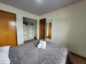 a bedroom with a bed with two towels on it at Casa vista das colinas in Gramado