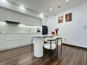 An KhêTera Apartment Hoàng Huy Commerce的厨房配有白色橱柜、桌子和凳子