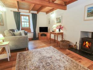 een woonkamer met een bank en een open haard bij 1 Rowes Cottages in Porthcurno
