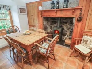 een eetkamer met een tafel en een open haard bij 1 Rowes Cottages in Porthcurno