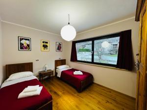 Un dormitorio con dos camas y una ventana. en La Rose du Prevot, en Fenis