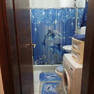 a bathroom with a blue shower curtain and a toilet at Tali in Novi Sad