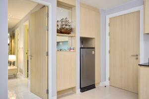 a kitchen with wooden cabinets and a refrigerator at Pattaya Jomtien Apartments l Guest Friendly l Waterpark Gym Sauna Jacuzzi in Pattaya South