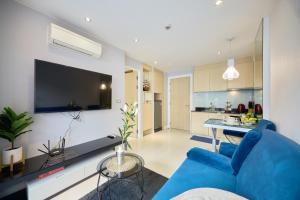 a living room with a blue couch and a kitchen at Pattaya Jomtien Apartments l Guest Friendly l Waterpark Gym Sauna Jacuzzi in Pattaya South
