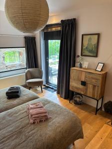 a bedroom with two beds and a chair and a window at B&B Terpboerderij Jannum in Janum