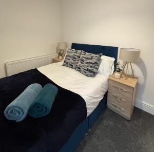 a bedroom with a bed with two blue towels on it at Spacious 3-Bedroom Apartment with Modern Comforts in Runcorn