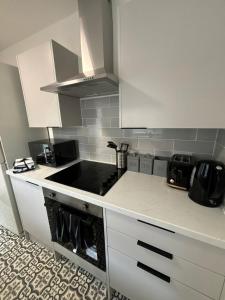 a kitchen with white cabinets and a stove top oven at Spacious 3-Bedroom Apartment with Modern Comforts in Runcorn +6 photos