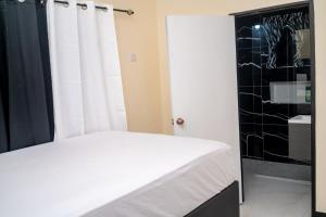 a bedroom with a white bed and a black wall at Dowayne 1bed 1 bath in gated community colbeck manor in Old Harbour +15 photos