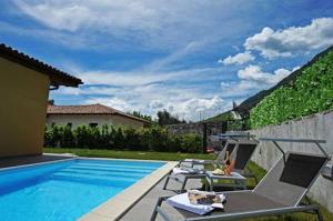 een zwembad met stoelen en een tafel naast een huis bij Villa Tremezzo in Tremezzo