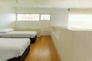 two beds in a small room with two windows at Loft Kala Zèna in La Maddalena
