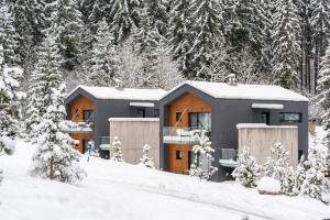 a building covered in snow with trees in the background at Malino Resort & Residences - Ski and Bike Apartments in Ružomberok