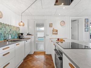 a kitchen with white cabinets and a counter top at Holiday Home Bela - from the sea by Interhome in Ringkøbing
