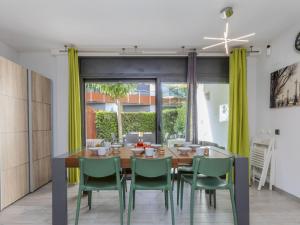 a dining room with a wooden table and green chairs at Holiday Home Sol Cambrils Park 28 by Interhome in Cambrils