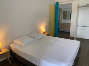 a bedroom with a large white bed and a bathroom at La Casa Moueza in Le Vauclin