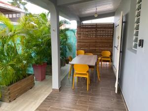 a dining room with a table and yellow chairs at La Casa Moueza in Le Vauclin