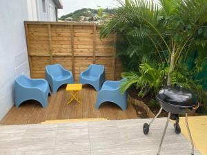 a patio with blue and yellow chairs and a grill at La Casa Moueza in Le Vauclin