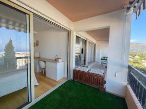 a balcony with a large window and green carpet at Beau 2 pièces grande terrasse vue mer in Roquebrune-Cap-Martin