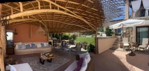 an outdoor patio with a couch and an umbrella at Villa JASMINE SMERALDA in Cala Bitta