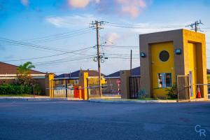 a yellow building with a fence in front of a street at Dowayne 1bed 1 bath in gated community colbeck manor in Old Harbour