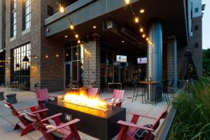 a fire pit in front of a building with red chairs at Archer Hotel Boston/Burlington in Burlington