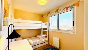a room with bunk beds and a desk and a window at Vue d'Opale - Appartement vue mer Stella-Plage in Stella-Plage