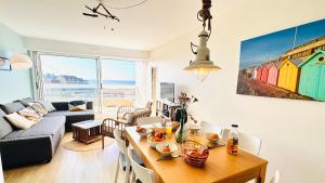 a living room with a table and a couch at Vue d'Opale - Appartement vue mer Stella-Plage in Stella-Plage
