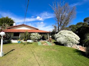 una casa con un patio verde con flores blancas en Chácara Aconchegante Vista Linda com Roupa de Cama, en Socorro