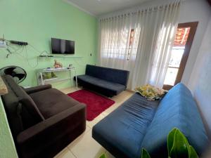 Una sala de estar con un sofá azul y un televisor en Chácara Aconchegante Vista Linda com Roupa de Cama, en Socorro