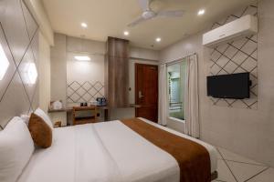 una camera da letto con un letto e una TV a parete di De Glance Hotel, Near Surat Railway Station a Surat
