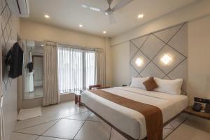 una camera da letto con un letto grande e una grande finestra di De Glance Hotel, Near Surat Railway Station a Surat Altre 80 foto