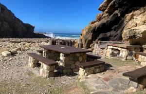 a picnic table and benches on a rocky beach at Forest Edge Hideaway -Six on Imbali in George