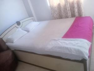 菩提伽耶Glamour palace的一张带白色床单和粉红色毯子的床