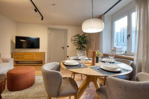 Steirerblicke City Apartments في غراتس: غرفة معيشة مع طاولة وكراسي وتلفزيون