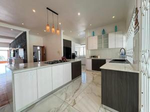 Chamane Place في ديربان: مطبخ كبير مع دواليب بيضاء وجزيرة كبيرة