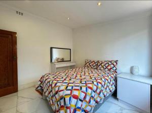 Chamane Place في ديربان: غرفة نوم مع سرير مع لحاف ملون +8 صور