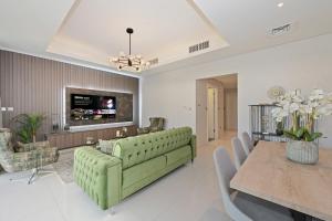 a living room with a green couch and a table at 3BR Luxurious Villa pool view DAMAC Hills 2 in Dubai