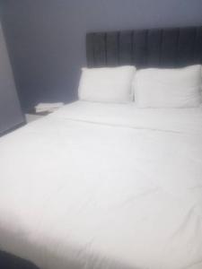 een bed met witte lakens en kussens in een kamer bij The Home Apartments in Kolwezi