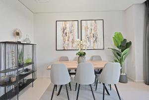 a dining room with a wooden table and white chairs at 3BR Luxurious Villa pool view DAMAC Hills 2 in Dubai