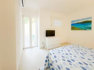 a white bedroom with a bed and a television at La Dimora di Bagnaja - HelloElba in Bagnaia