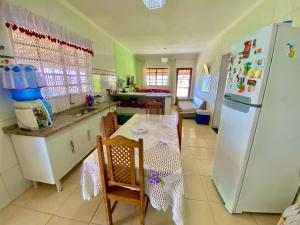 Una cocina con una mesa y un refrigerador blanco. en Chácara Aconchegante Vista Linda com Roupa de Cama, en Socorro