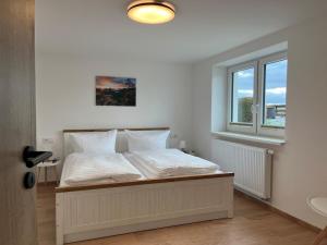a bedroom with a bed with white sheets and a window at 4-Steine-Blick, Wohnung "Zum Winterberg" in Schöna